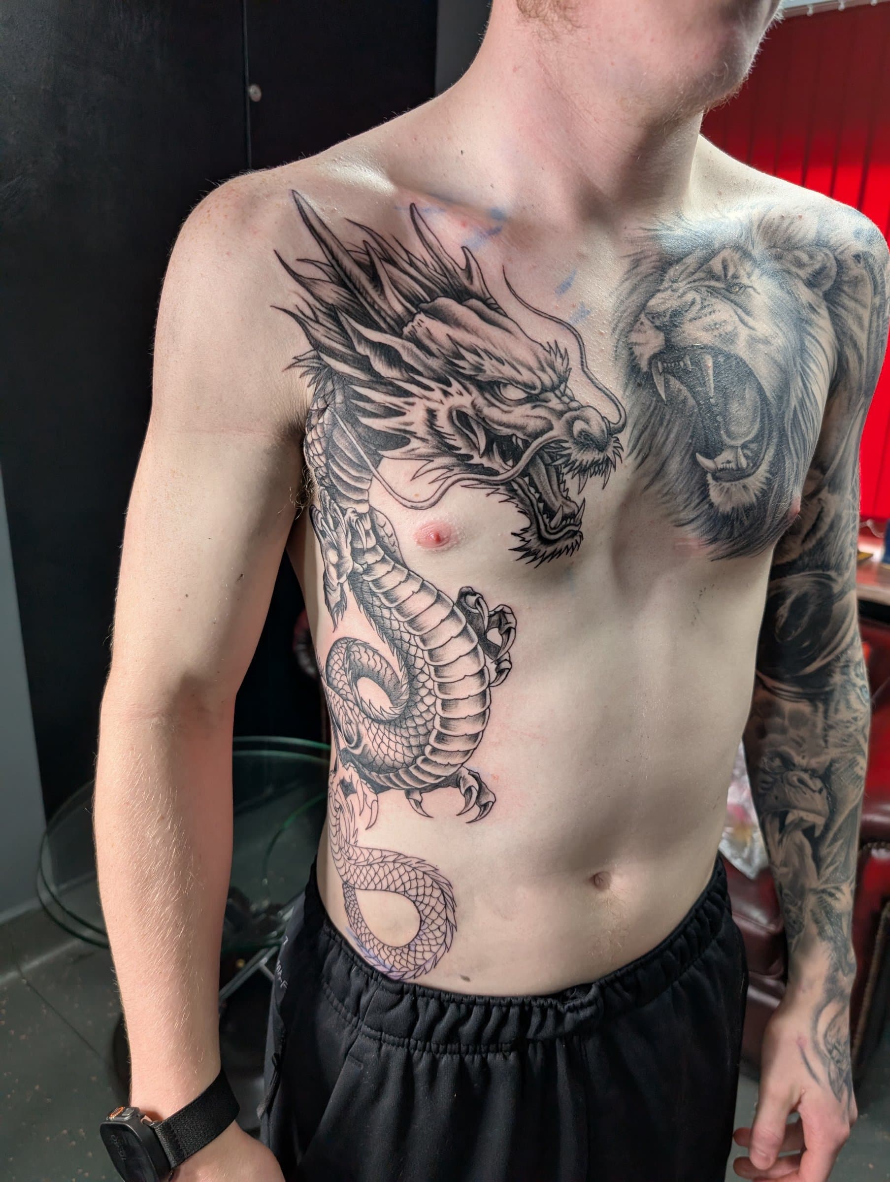 Intricate black and grey dragon and lion designs with detailed shading on the chest