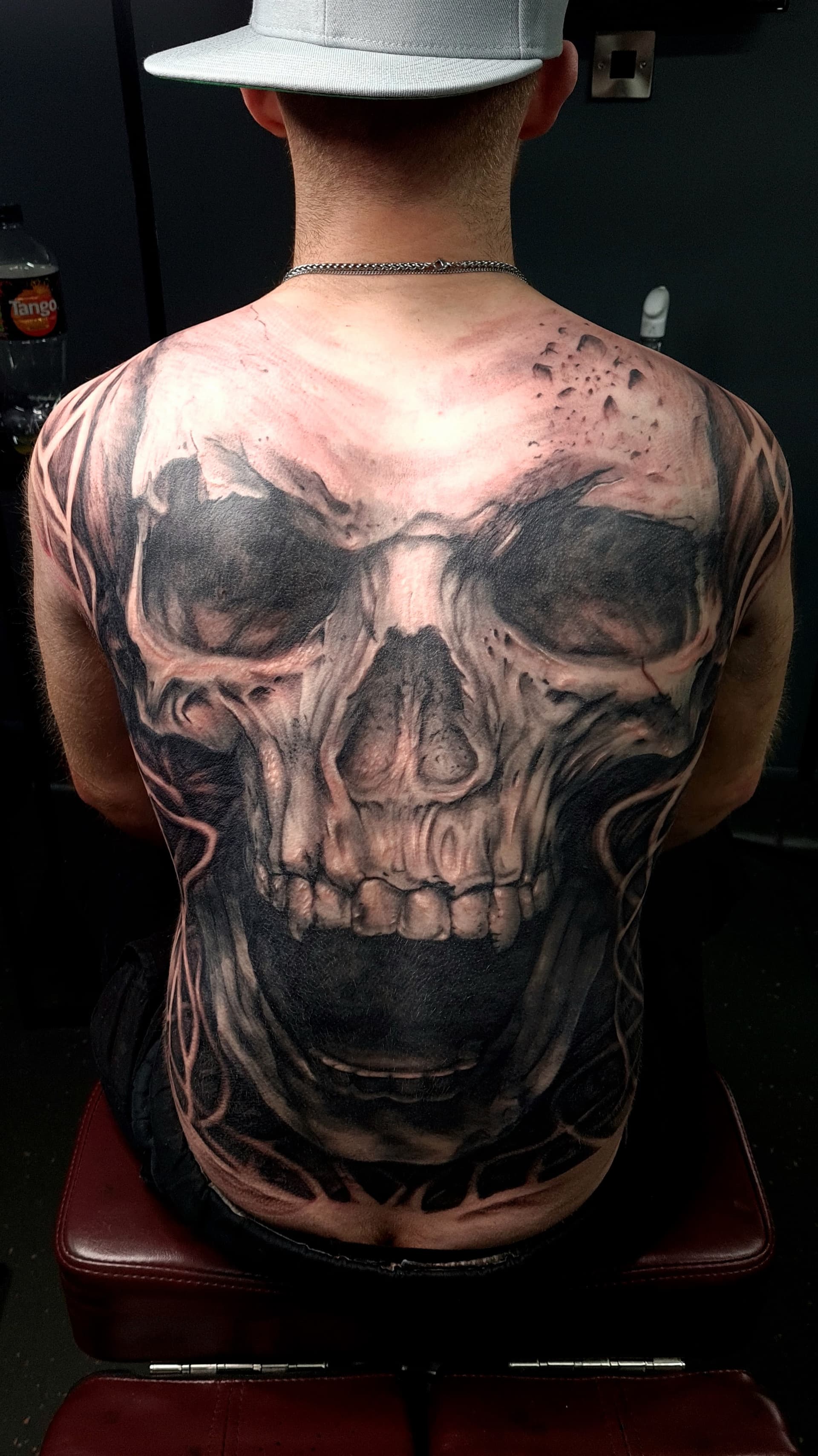 Detailed black and grey realism skull tattoo on a man's back.
