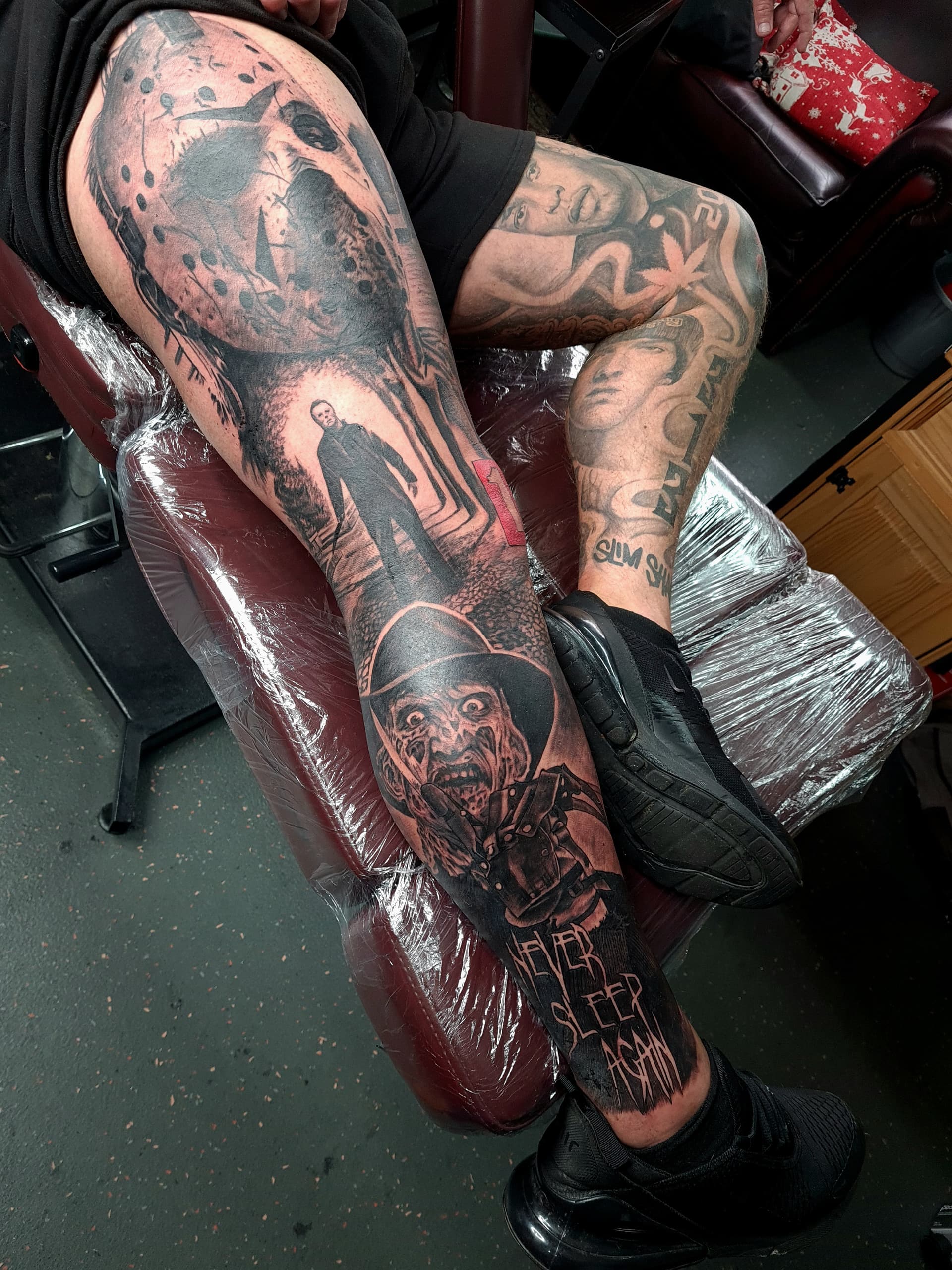 Detailed black and grey realism tattoo depicting horror characters on leg.