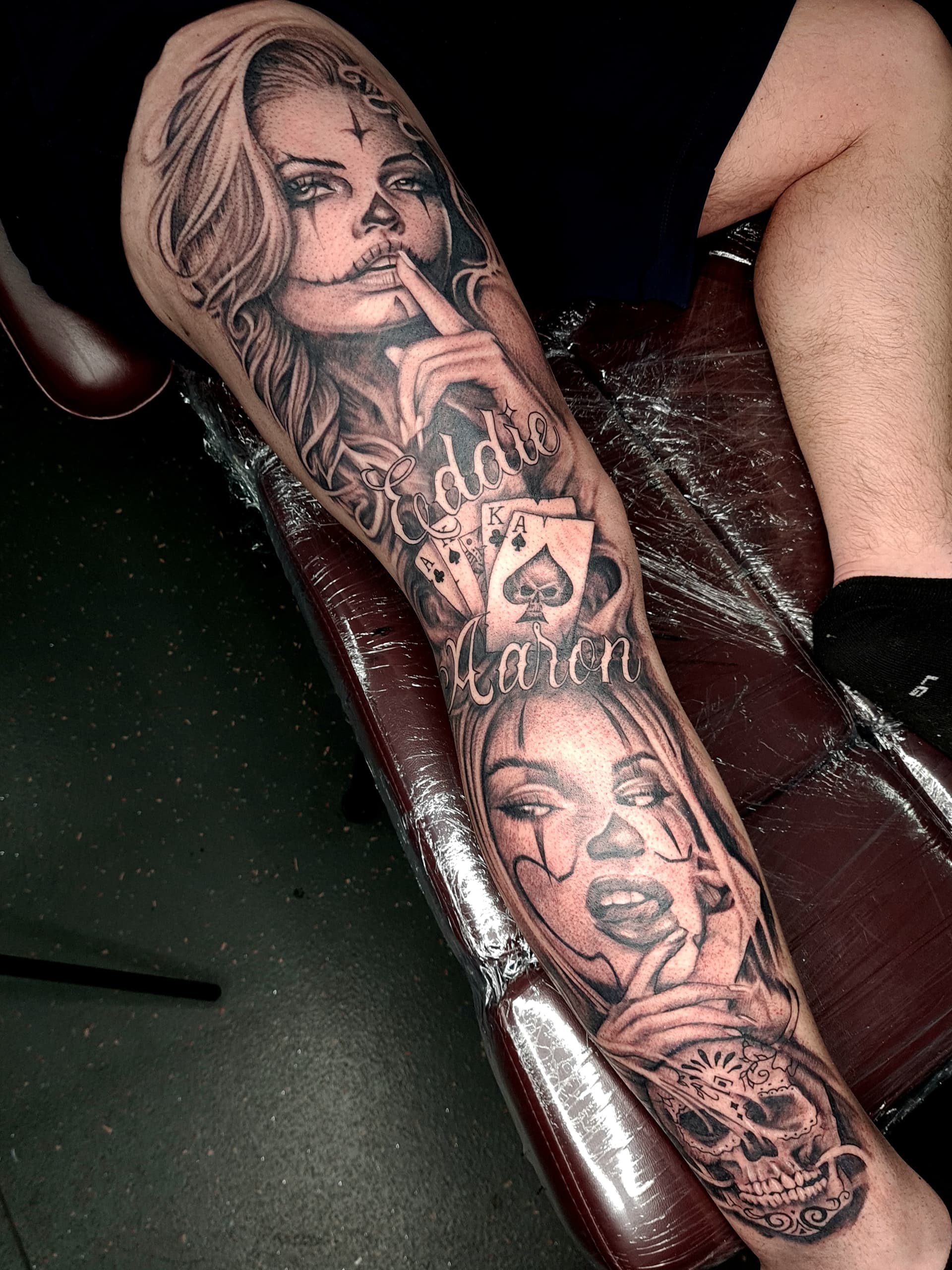 Realism tattoo featuring a woman, playing cards, and lettering on leg.