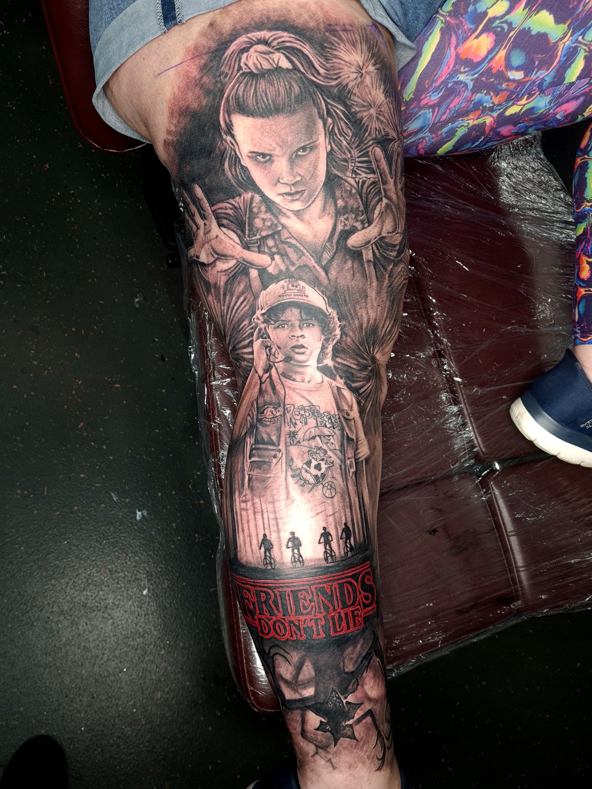 Realism tattoo sleeve featuring characters from Stranger Things, black and grey style.