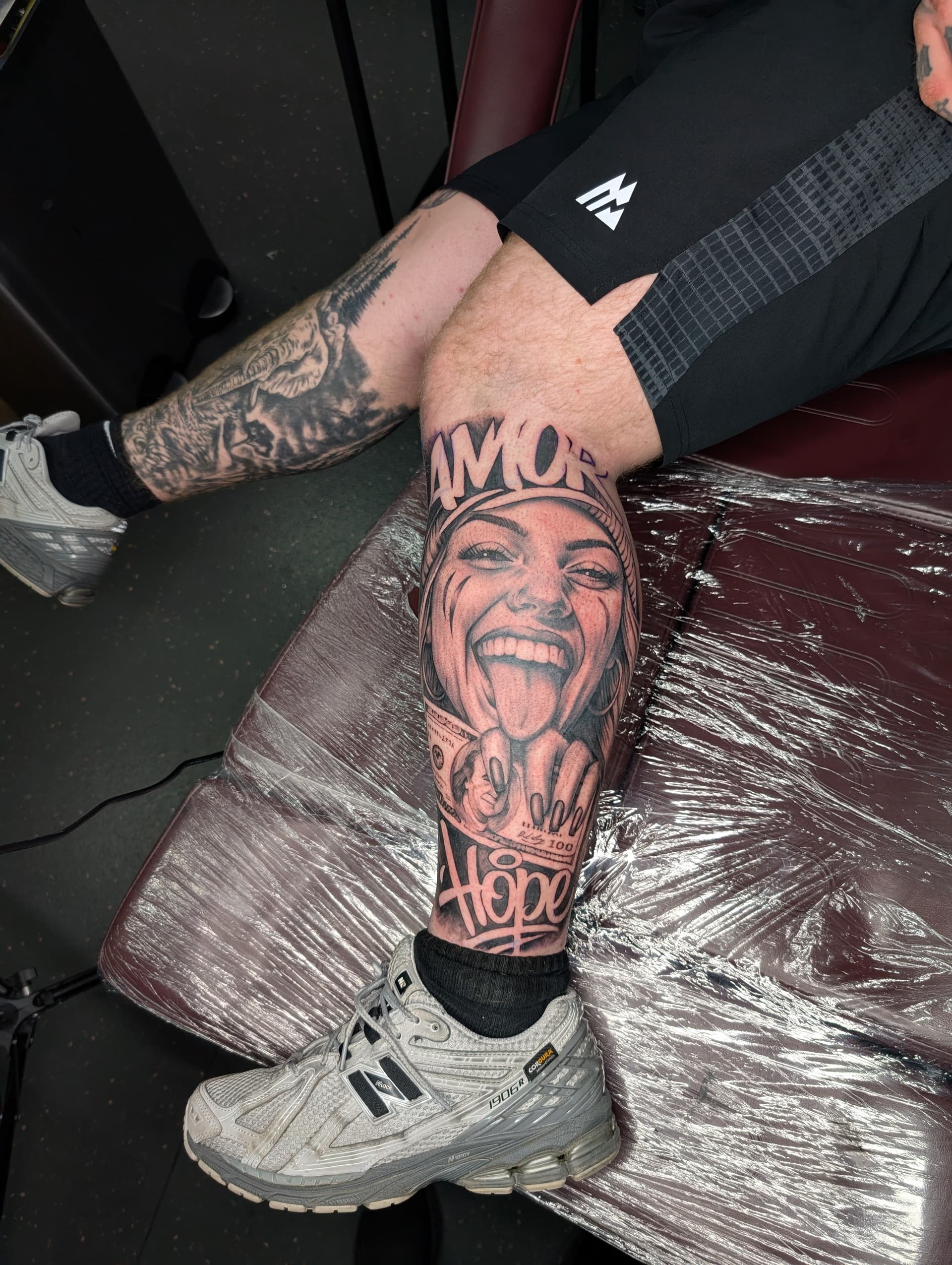 Black and grey realism portrait of a woman with the words 'Amor' and 'Hope' on leg.