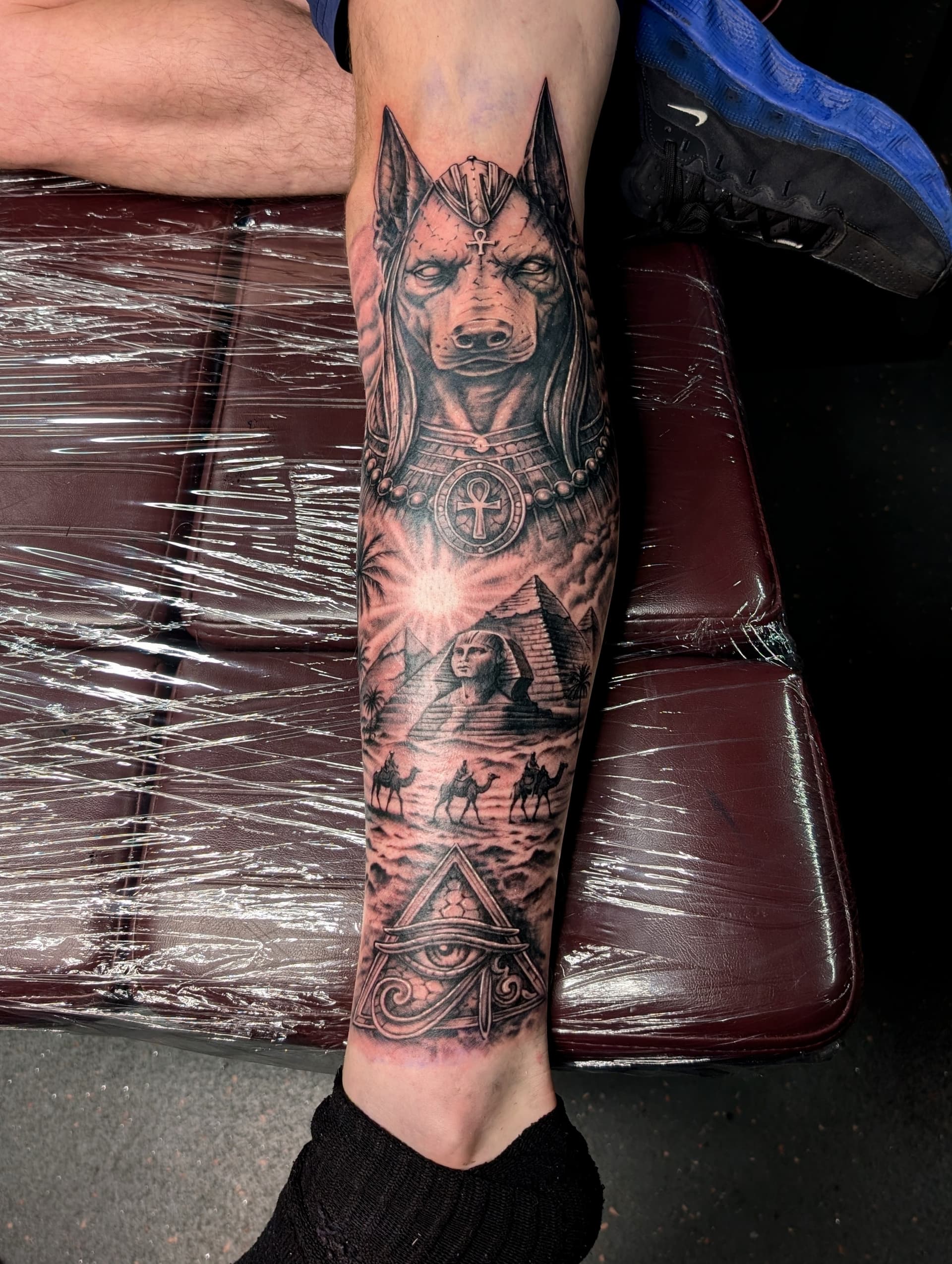Black and grey realism tattoo of Anubis, the Sphinx and pyramids on the calf and shin